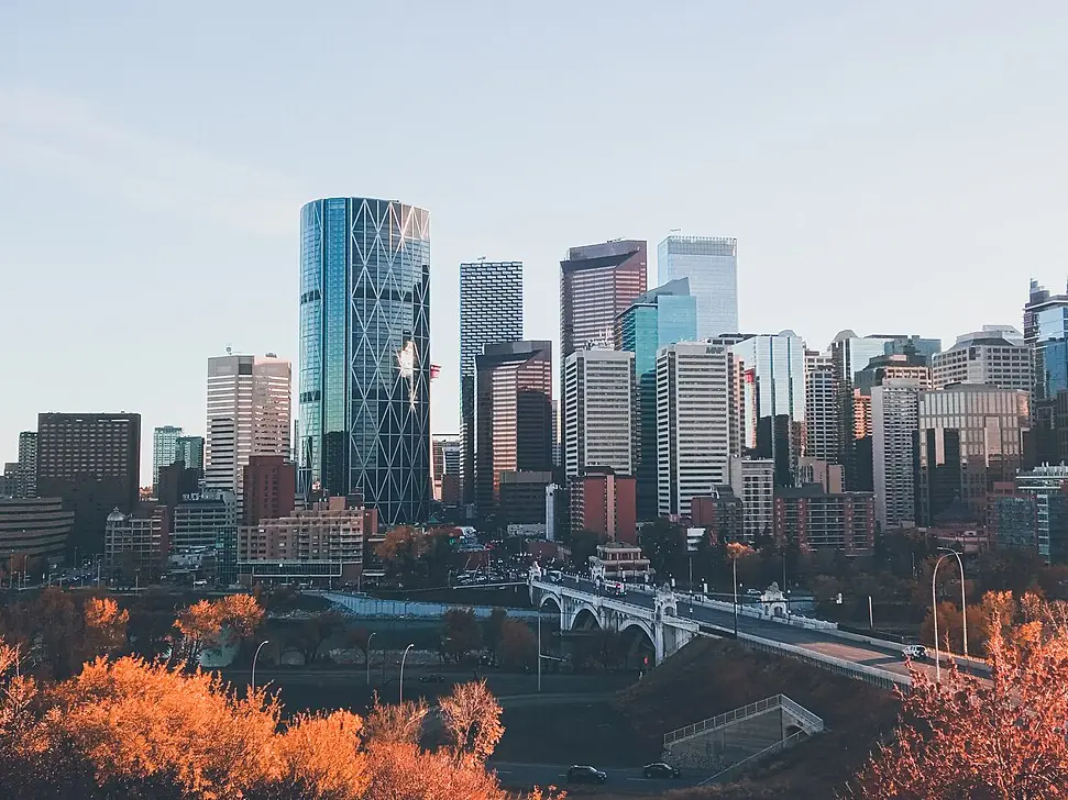 Downtown Calgary towers above the Bow River and the Centre Street Bridge, with orange autumn trees in front